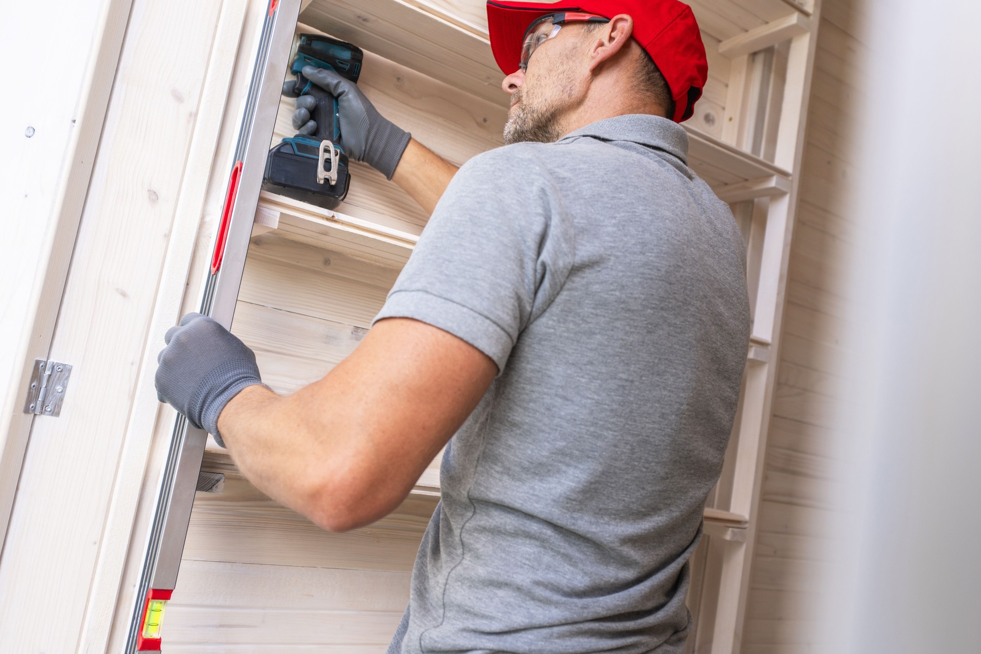 Carpenter Installing Shelving in a Home Workshop During Daylight Hours
