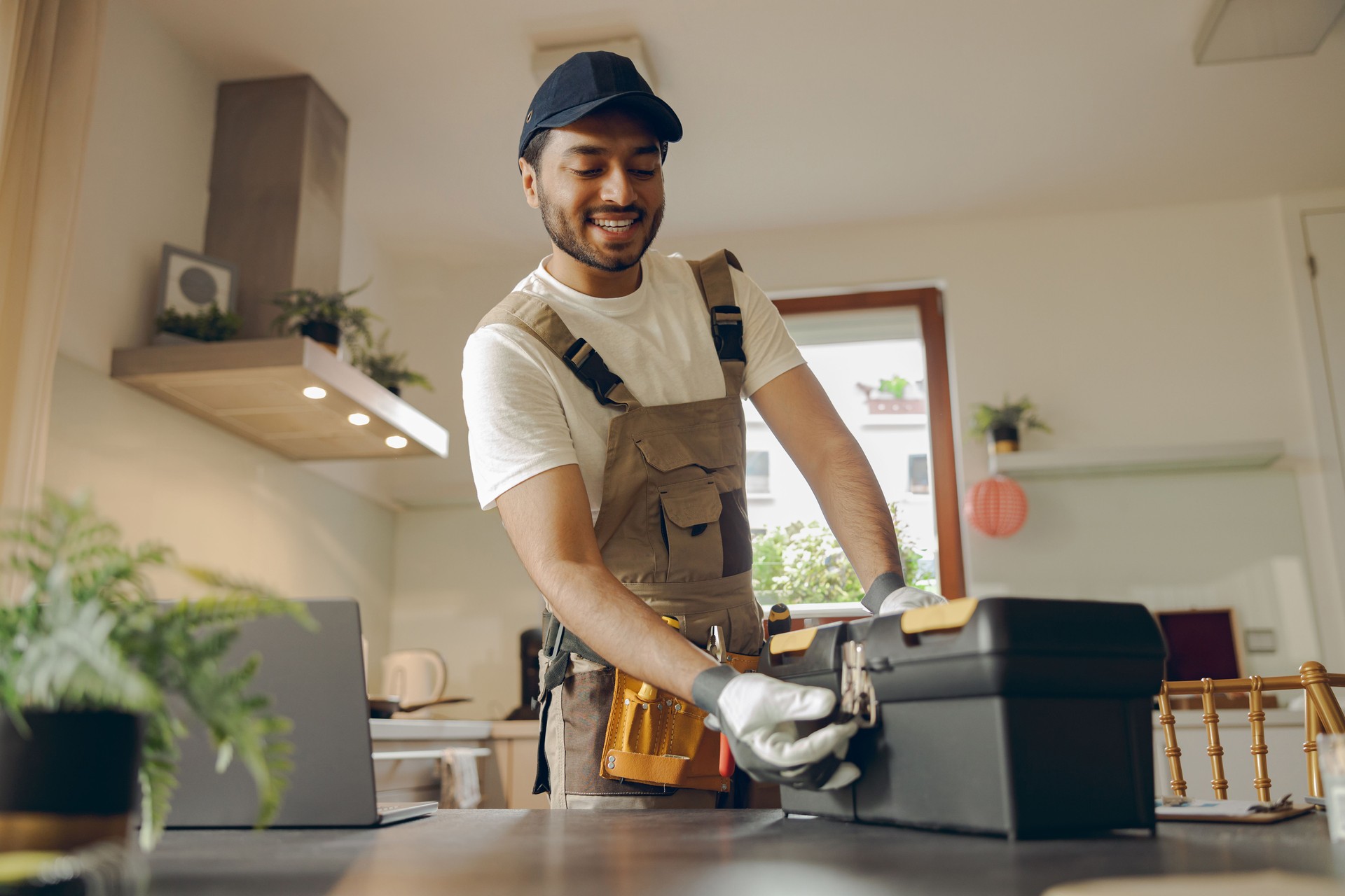 Smiling professional handyman standing on home kitchen and open his tool bag